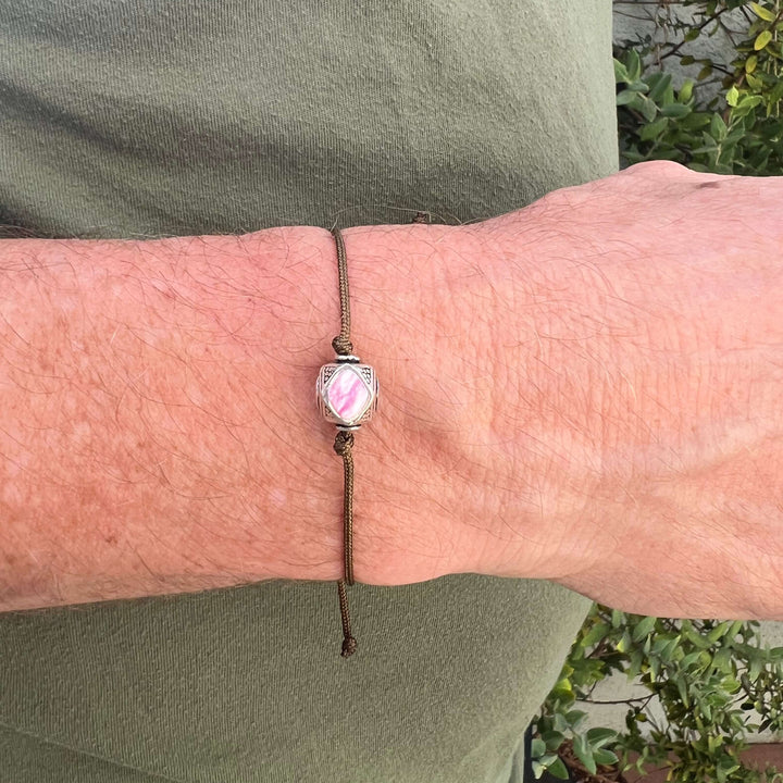 close up of model wearing mens Sterling silver breast cancer cell image in resin pendant on brown adjustable cord