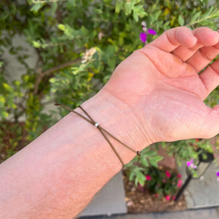 back of mens Sterling silver breast cancer cell image in resin pendant on brown adjustable cord on model