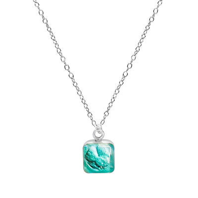 close up of infertility awareness necklace with early embryo in teal in square pendant necklace