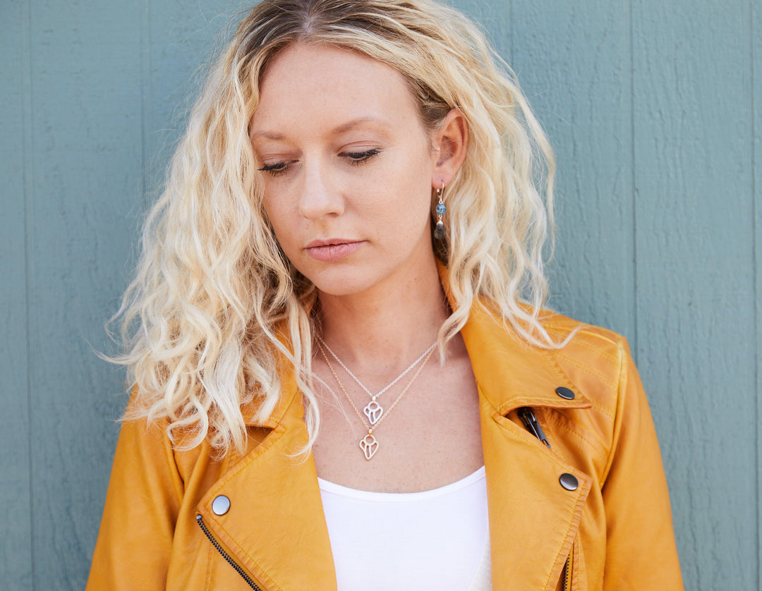 Model wearing both the silver and gold guardian angel necklace in the 16 and 18 inch lengths