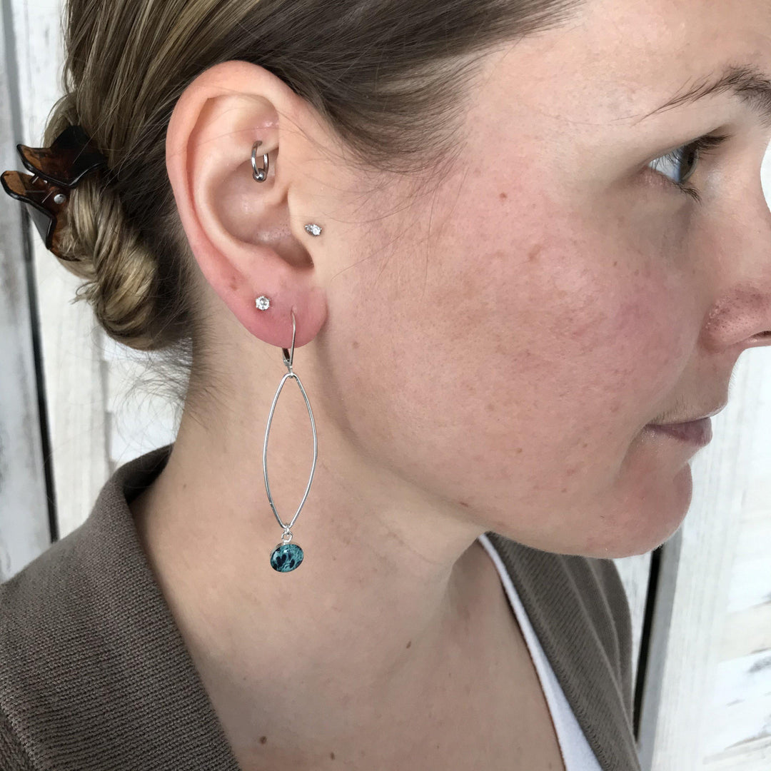 Model wearing teal ovarian cancer earrings in sterling silver. 