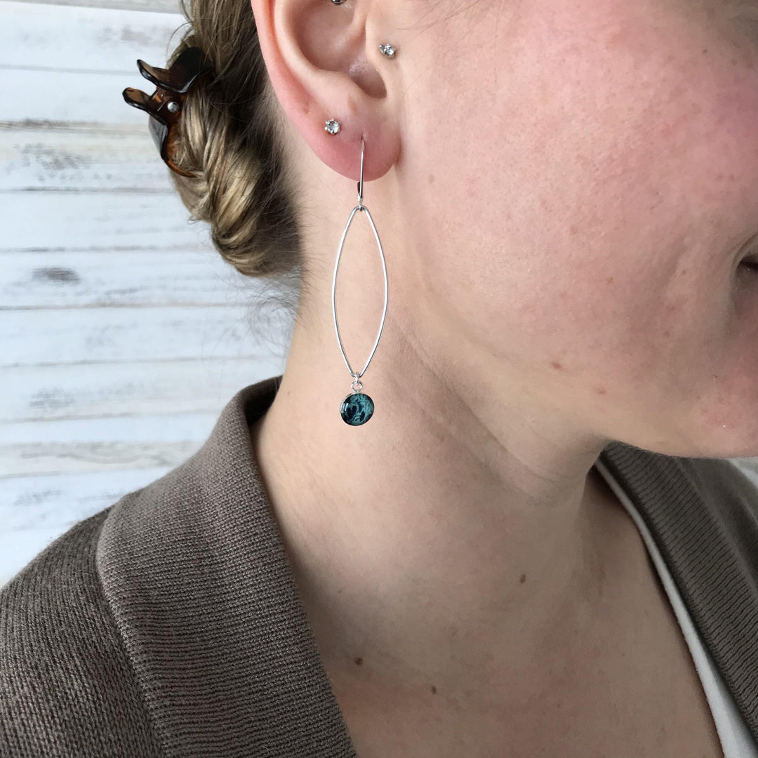 Model wearing Teal ovarian cancer earrings in sterling silver. 